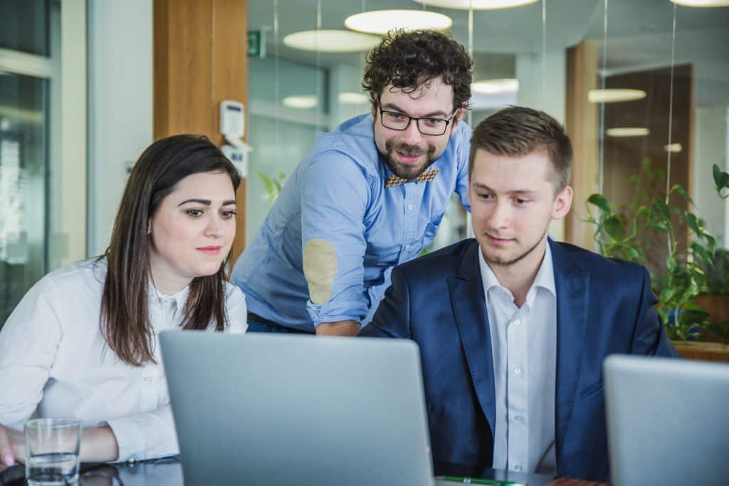 Tres compañeros de un equipo comercial revisando juntos oportunidades de venta en un portátil